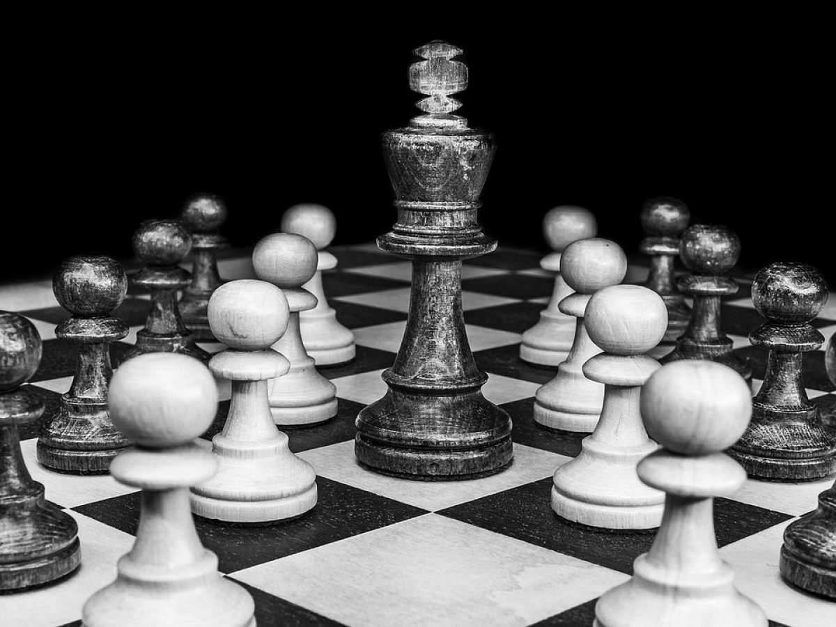 棕色尘埃 战棋回合制手游的室内布阵界面，六格棋盘上分布着前排承伤与后排输出角色，蓝青色技能特效在木质桌面上映出微光，屏幕反光里能看见玩家按在边缘的手指